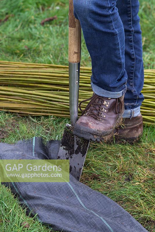 Use the spade to tuck in and secure the weed control fabric
