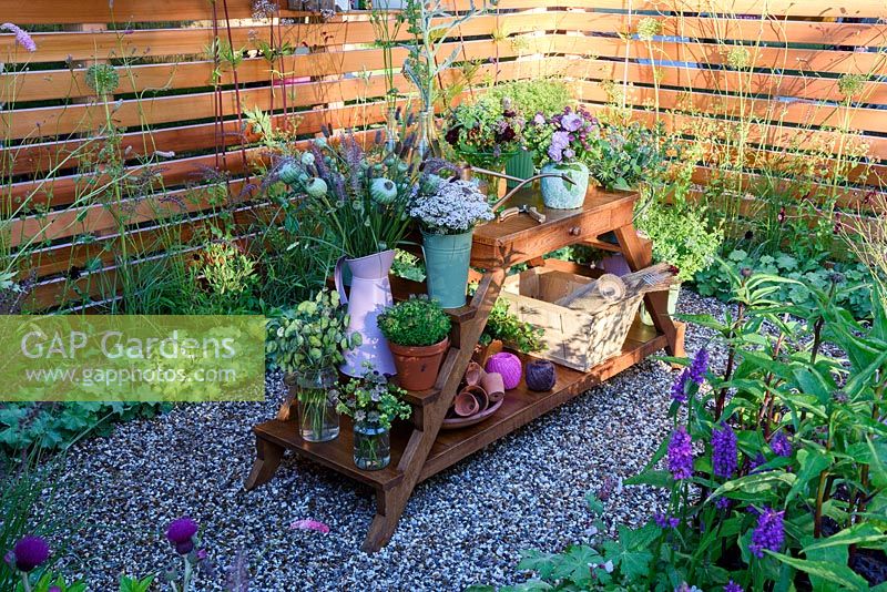 Katie's Garden. Cut flowers in vase's on oak table in gravel bed. Designers: Carolyn Dunster and Noemi Mercurelli. Sponsors: Katie's Lymphoedema Fund, RHS Hampton Court Palace Flower Show 2016