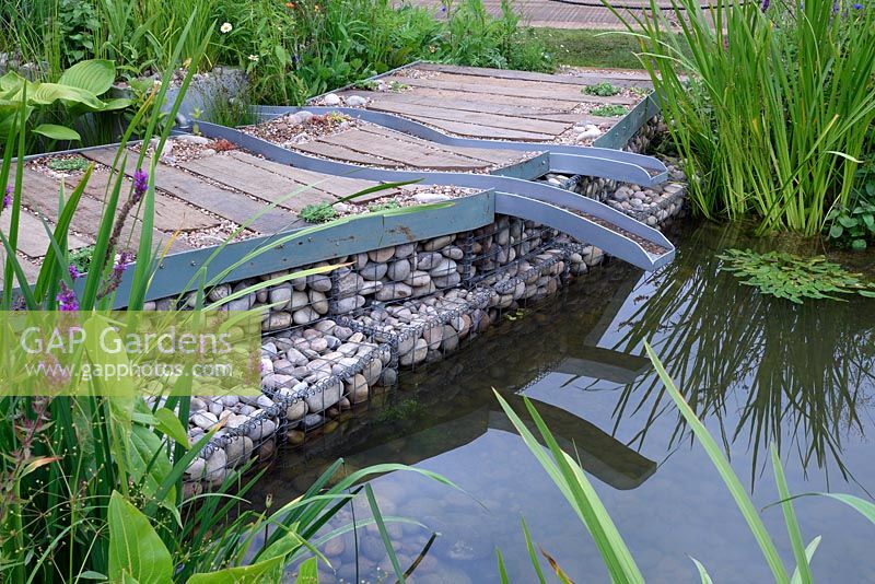 The WWT Working Wetlands Garden. Plank wood path in wetland garden. Designer: Jeni Cairns, Sponsors: WWT. RHS Hampton Court Palace Flower Show 2016