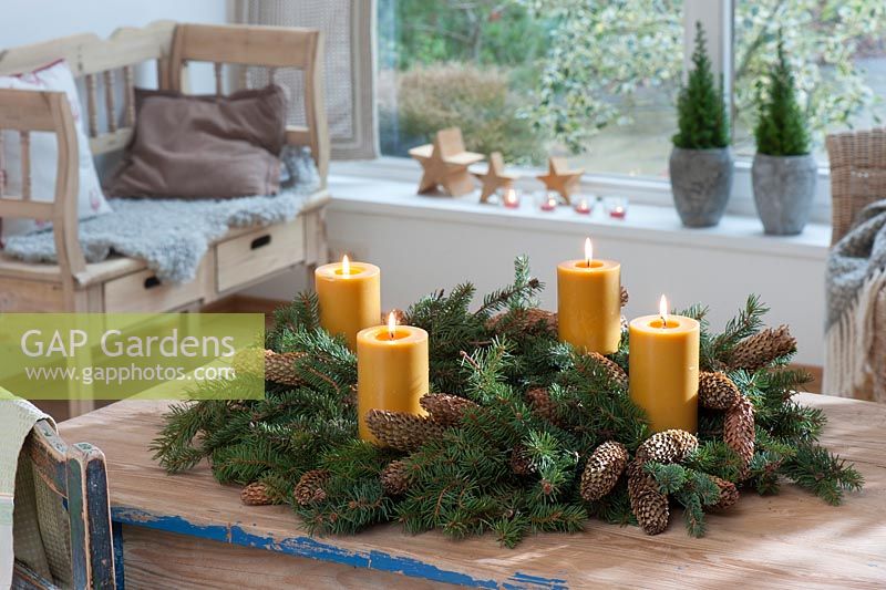 Advent wreath made from branches of Picea with cones and beeswax candles 