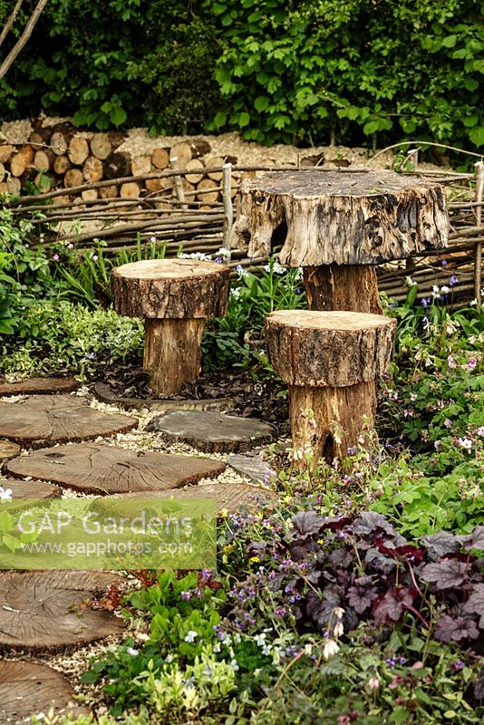 Stepping stones, table and stools made from tree trunks surrounded by woodland planting - The Woodcutter's Garden - RHS Malvern Spring Show 2016. Designer: Mark Walker, Sponsor: Howards Motors