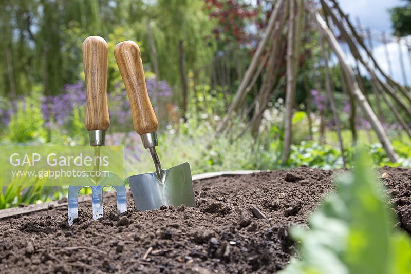 Garden trowel and hand fork in a raised bed