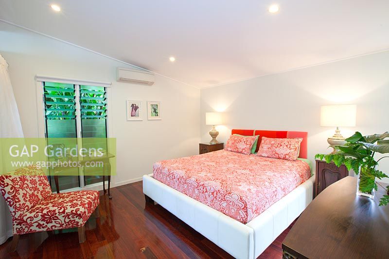 Interior of a B and B in tropical northern Australia showing a queen bed on polished floorboards and assorted furniture.