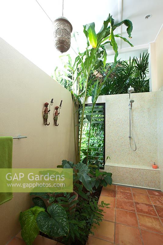 Outdoor shower in a bed and breakfast accommodation featuring terracotta tiles, louvred windows and shade loving plants