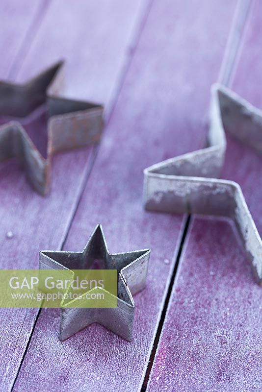 Metal star shaped cookie cutters on a frosted purple table