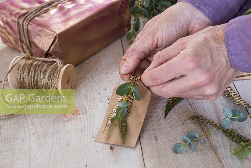Creating a natural gift tag by combining Eucalyptus and gold spray painted fern foliage