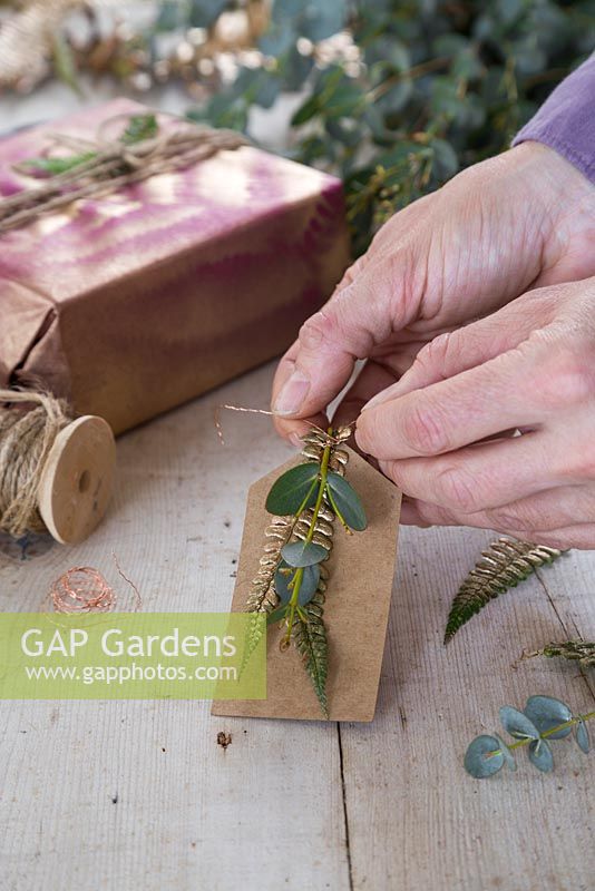 Creating a natural gift tag by combining Eucalyptus and gold spray painted fern foliage