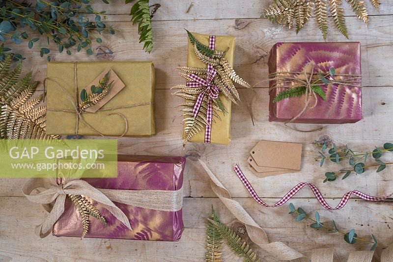 A variety of presents decorated with natural Fern and Eucalyptus foliage and spray painted imprints