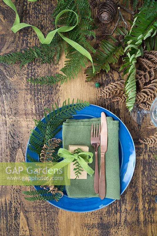 A table place setting with gold spray painted Fern and green Fern fronds