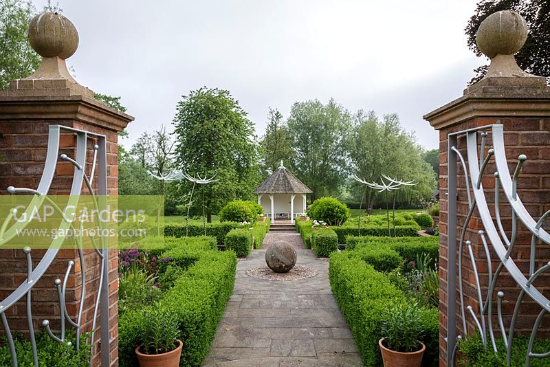 A view through the entrance gates into the formal gardens. Mitton Manor, Staffordshire. 