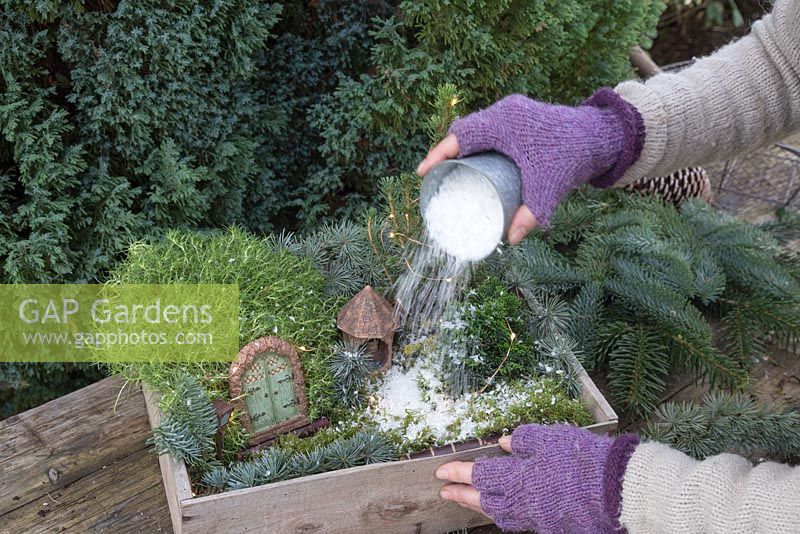 Pouring artificial snow over winter wonderland box to create a snow scene