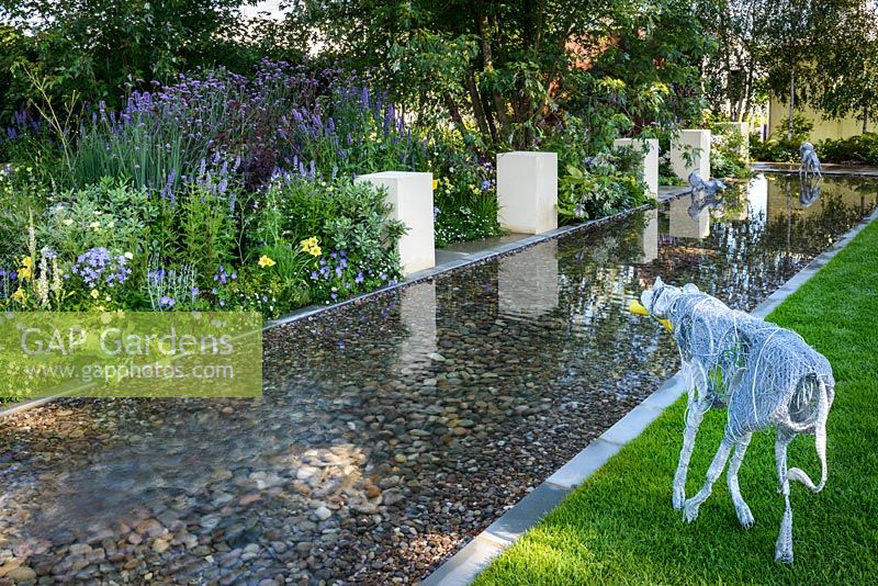 Wire dogs sculptures in a rectangular pool with pebbles and white blocks reflected in the water.  The Dog's Trust: 'It's a Dog's Life', Hampton Court Flower Show, July 2016