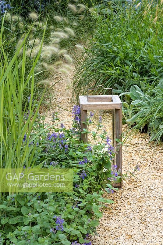 A storm candle on gravel bed with  Pennisetum villosum and Nepeta x fassenii - The Drought Garden, RHS Hampton Court Palace Flower Show 2016