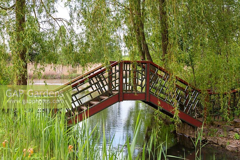 Red and black-painted Chinese bridge with a geometric pattern links two of the islands in the garden. These were made from the spoil excavated from the lake which mean they are far more fertile than the surrounding soil.