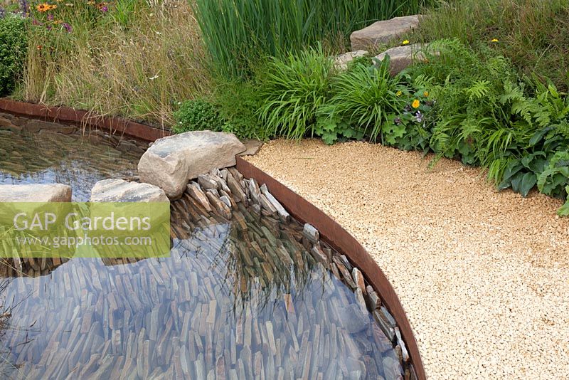 Stream banked by grasses and wildflowes in the Zoflora Outstanding Natural Beauty Garden at RHS Hampton Court Flower Show 2016