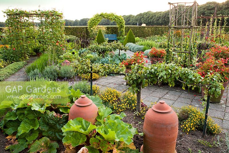 Kitchen garden trained fruit trees, rustic supports and beds of herbs and vegetables. Design: Dineke Logtenberg