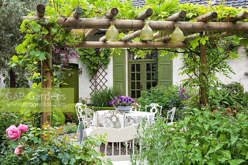 Pergola covered with grapes and Wisteria with hanging wasp traps. Design: Dina Deferme