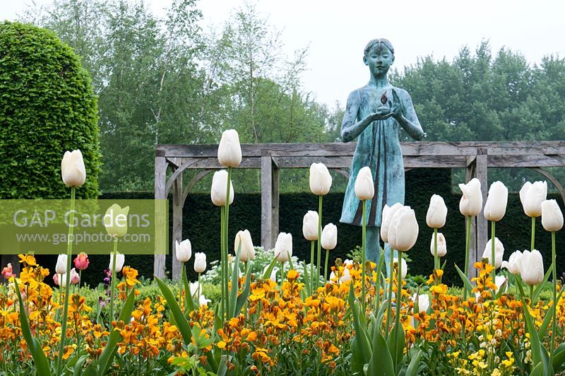 Tulipa 'Maureen' and Erysimum Cheiri 'Fire King' surrounding the statue, 'The Lamp of Wisdom' by Natham David in the formal garden at Waterperry.