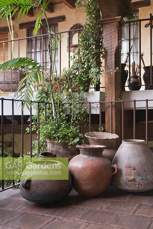 A collection of handmade earthenware pots on balcony with rusted style iron railings