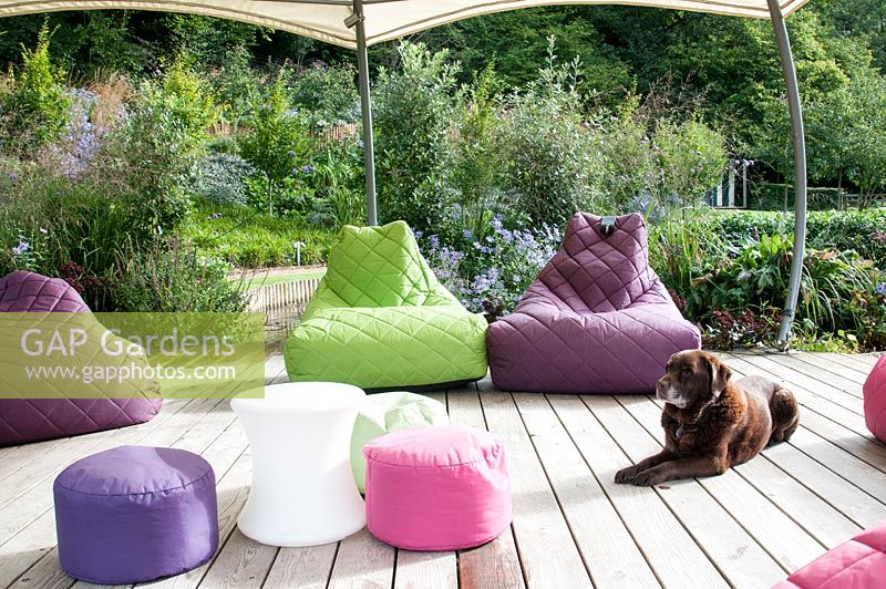 Modern garden with decking and multi coloured soft cushion seats under gazebo