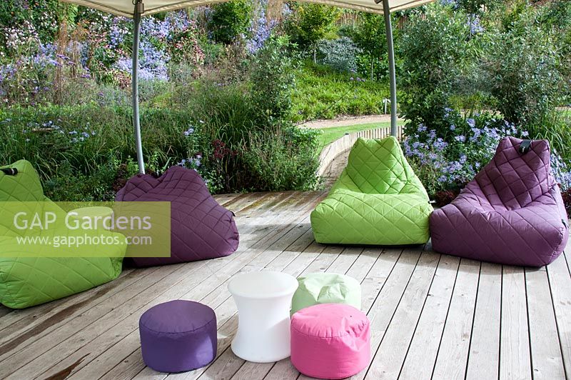 Modern garden with decking and multi coloured soft cushion seats under a gazebo