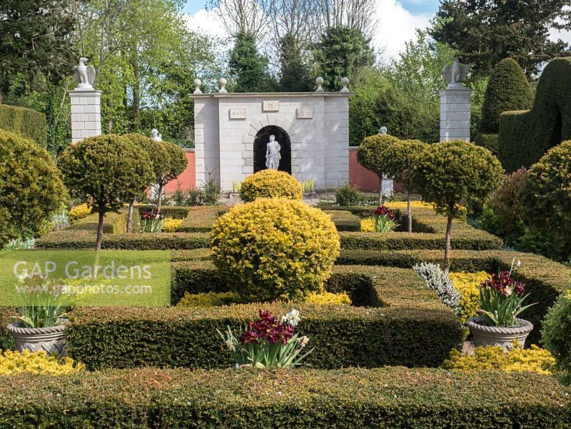 The Laskett Gardens- The Yew garden with its Taxus baccata hedges and topiary leading the eye to Nymphauem statues and wall in a clasical Greek, Roman style.  The wall is inscribed with Sir Roy Strongs initials and dates..  Egals adorn the two pillars.