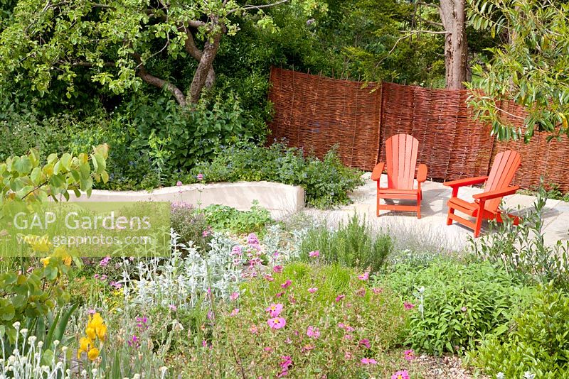 Decorative painted red garden seats on patio with Cistus, Iris and Stachys 
