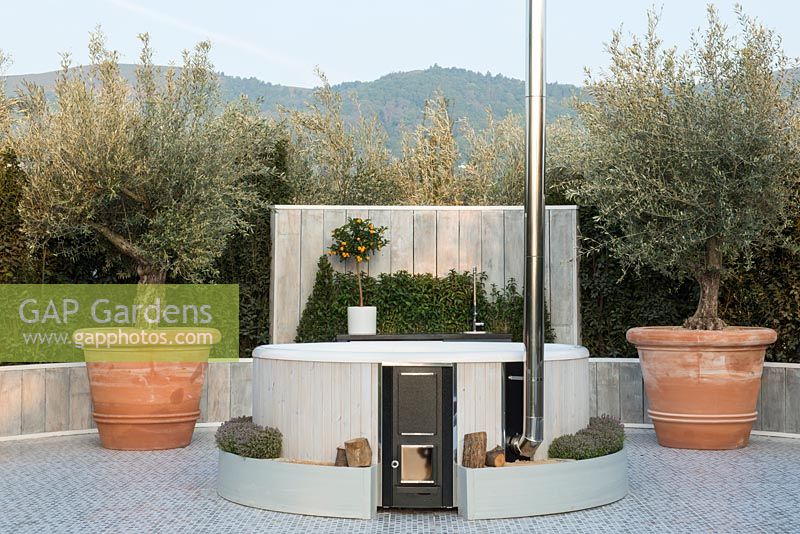 Hot tub fuelled by log burner, Olive trees in terracotta planters - The Retreat, RHS Malvern Spring Festival 2017 - Design: Villaggio Verde