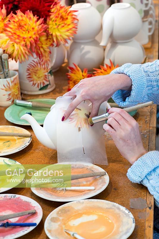 The second of six stencils is applied to the teapot, and more details of the flower are carefully applied.