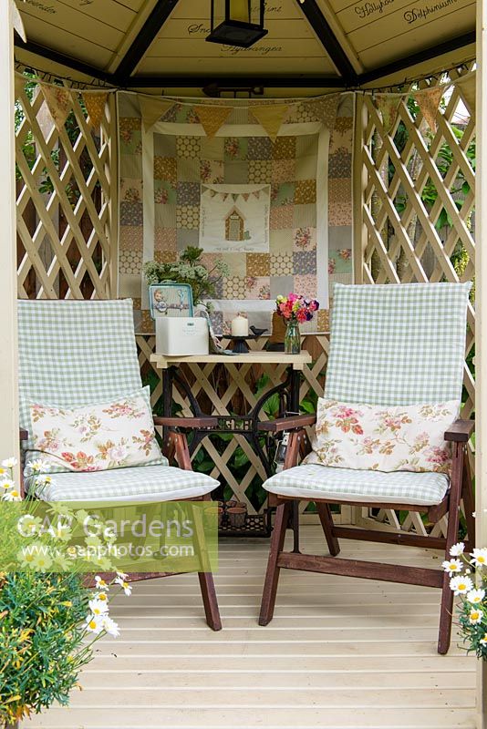 A modern gazebo, a covered seating area decorated with bunting and a wall hanging. The table's support is made from the iron base of an old sewing machine.