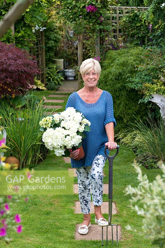 Lynne Obrey-Quick, with a potted hydrangea, in her small suburban garden.