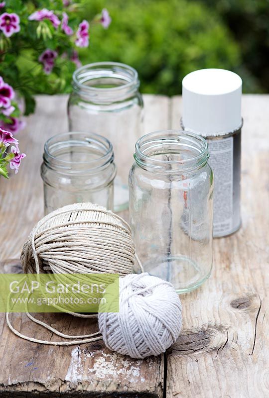 Making garden lanterns. Ingredients required: jam jars, string, white spray paint