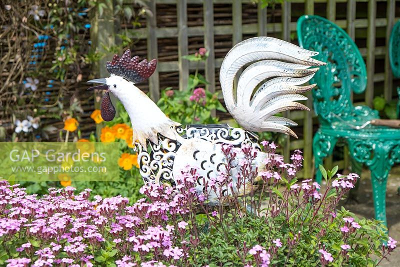 A garden in summer with a metal chicken ornament.