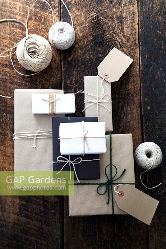 Lots of presents wrapped with brown and white paper and fastened with string, with gift tags and string.