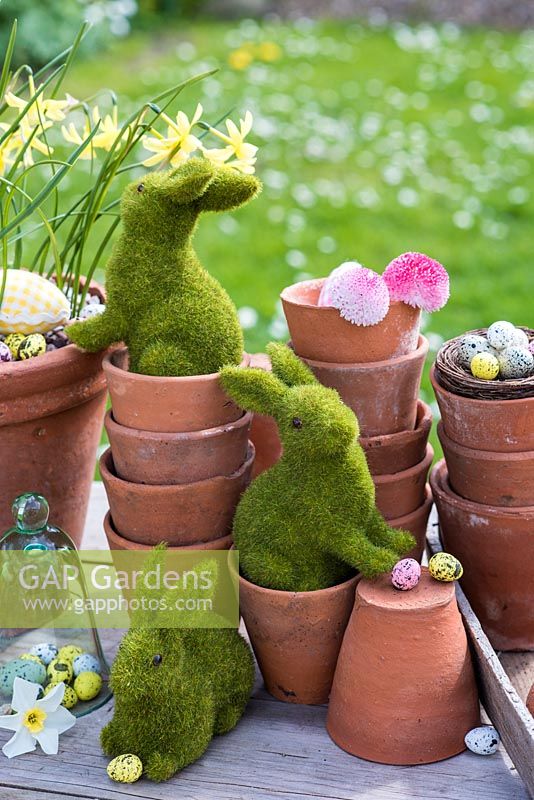 Easter bunnies playing in terracotta pots with eggs and flowers