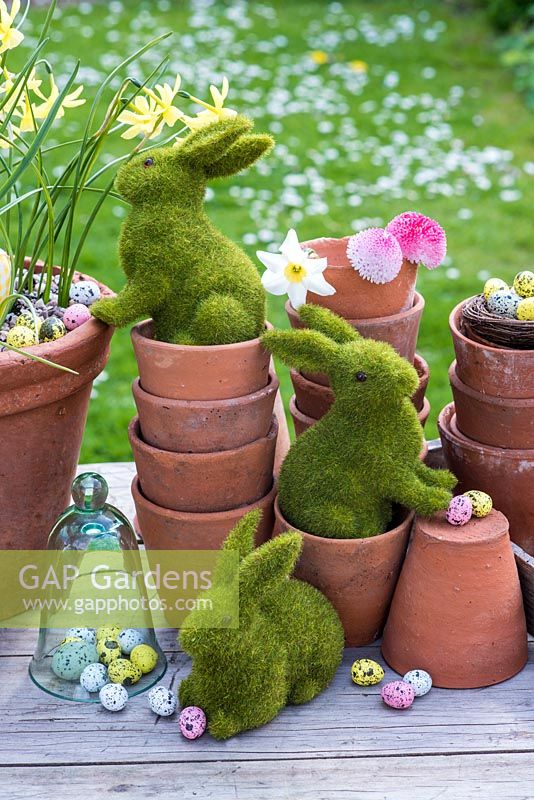Easter bunnies playing in terracotta pots with eggs and flowers