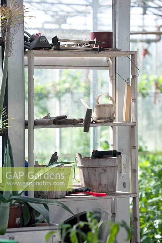 Wooden shelf with wooden buckets and other tools in the greenhouse.
