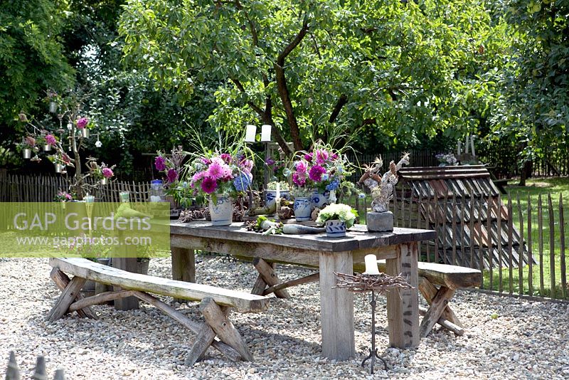 Decorated table in the garden with hydrangea and dahlias in jars
