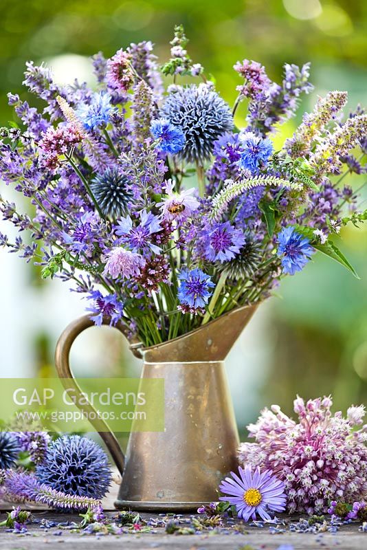 Jug of blue and purple summer flowers. Cornflower, Echinops ritro, chives, origanum, veronicastrum, elephant garlic, lavandula, Verbena bonariensis.