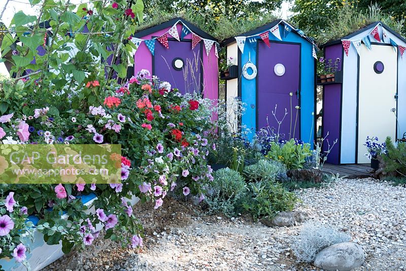 Fun by the sea, with an old rowing boat in front of a line of beach huts is planted with, blue, white and purple petunias, ivy leaved geraniums and zonal geraniums. Designed by: Tony Wagstaff, Sponsored by Sovereign Play Equipment.