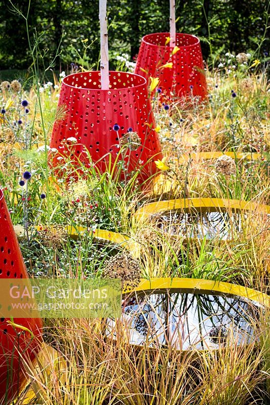 Hampton Court Flower Show, 2017. Kinetica Garden. Red planters with Betula jacquemontii above small circular ponds.