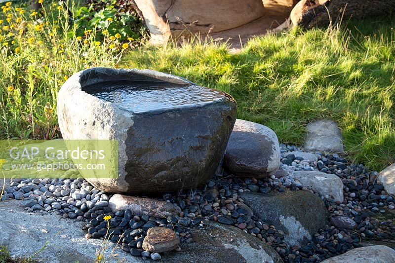 Hampton Court Flower Show, 2017. The 'Zoflora and Caudwell' Children's Wild Garden. Small rock pool water feature on stream bed in wild garden