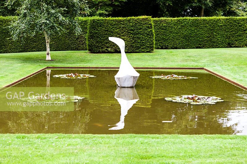 The Pond Garden: Formal pool surrounded by hedge of Taxus Baccata. Sculpture of White marble called 'Hokusai's Boat' by Jessica Walters, Farleigh House, Farleigh Wallop, Hampshire. June. Designer Georgina Langton.