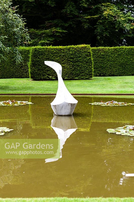 The Pond Garden: Formal pool surrounded by hedge of Taxus baccata. Sculpture of White marble called 'Hokusai's Boat' by Jessica Walters, Farleigh House, Farleigh Wallop, Hampshire. June. Designer Georgina Langton.