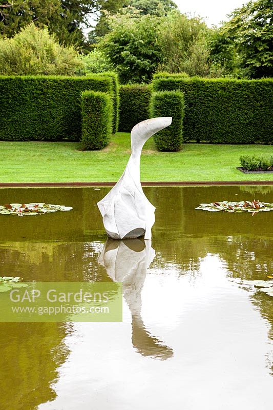 The Pond Garden: Formal pool surrounded by hedge of Taxus Baccata. Sculpture of White marble called 'Hokusai's Boat' by Jessica Walters, Farleigh House, Farleigh Wallop, Hampshire. June. Designer Georgina Langton.