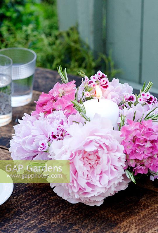 Candle centerpiece floral arrangement with peonies, hydrangea, rosemary foliage and geraniums
