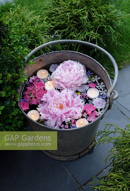 Candles floating in a vintage metal bucket with Peonies, Hydrangea, Jasmine and Campanula