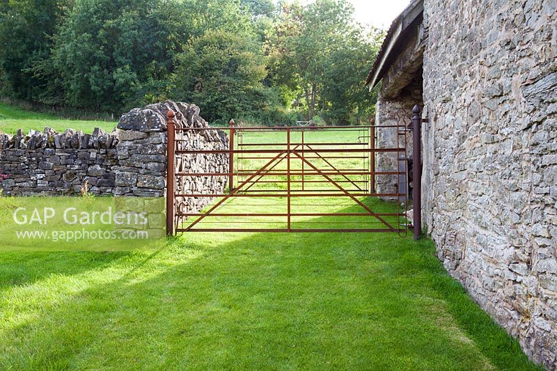 Rusty iron field gates attached to an old stone barn