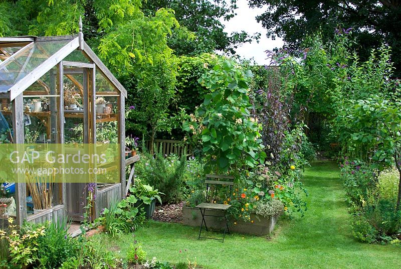 Garden view with wooden greenhouse and vegetable beds