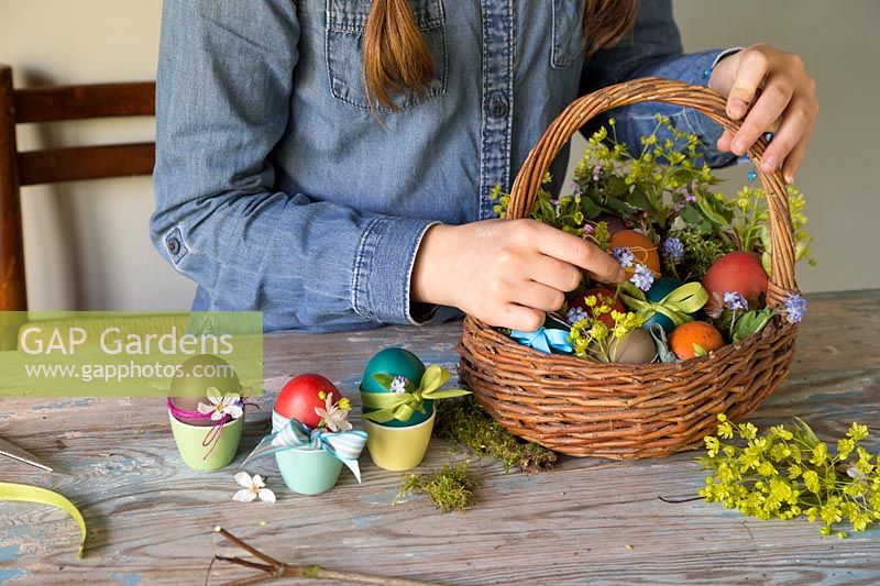 Placing decorated dyed easter eggs into basket